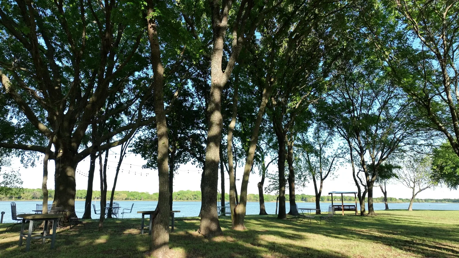 Picnic tables in the shade of the oaks along the private Lake Lewisville shoreline at Waterfront Hideaway Ranch